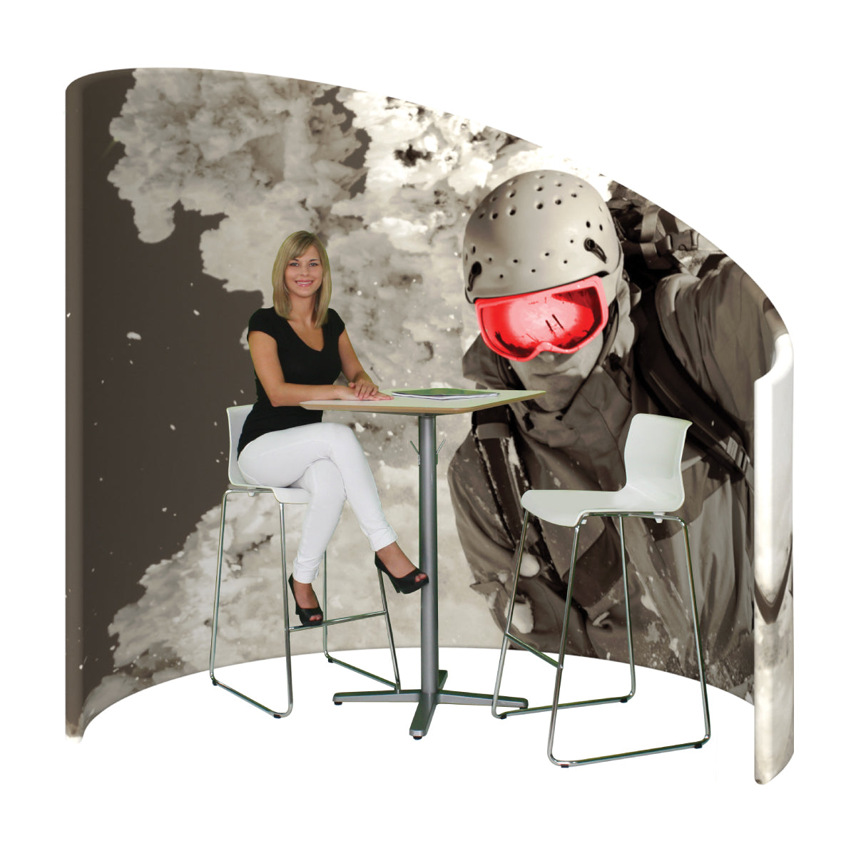 Trade show booth with curved backdrop featuring skier graphic and seating area with table and stools