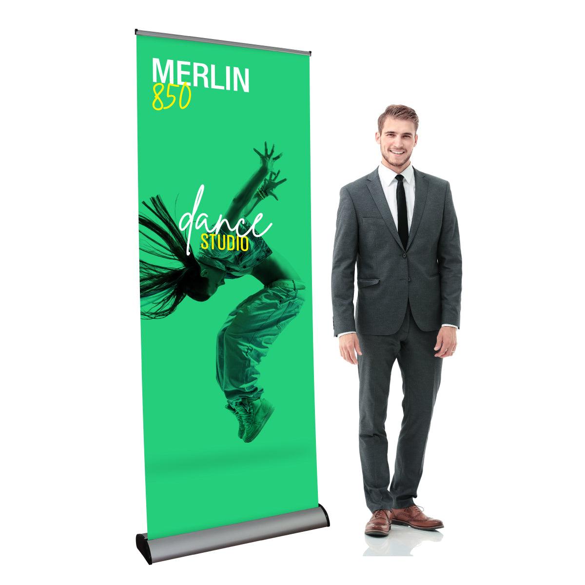 Retractable banner stand displaying dance studio advertisement with a man in business suit standing next to it for trade shows