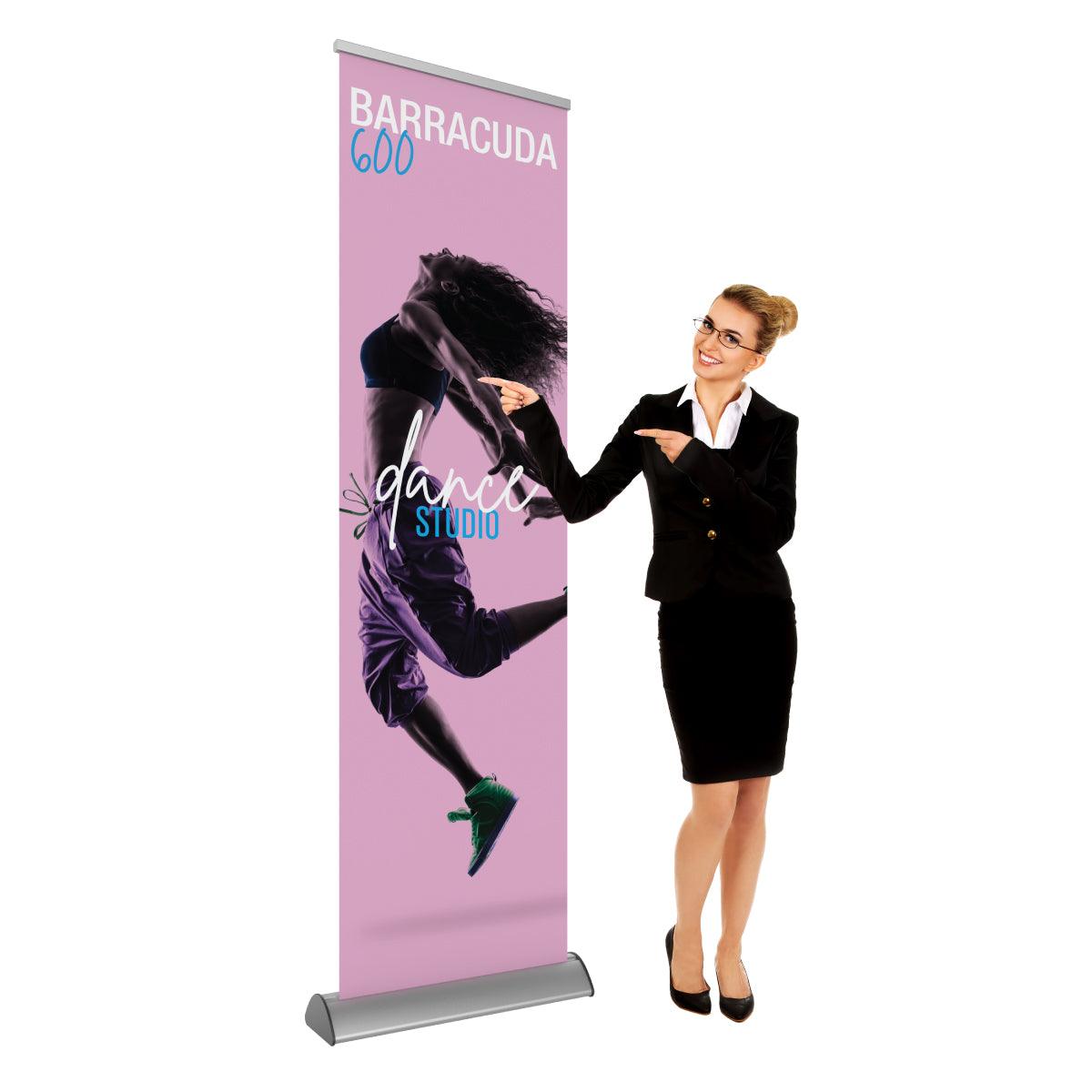 Professional woman in business attire pointing at a Barracuda 600 retractable banner stand promoting a dance studio, ideal for trade shows and exhibitions
