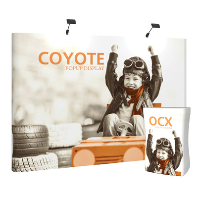 Trade show popup display featuring a child pilot image with raised arms, framed by stacked tires and a case to counter display
