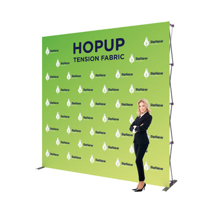 Large tension fabric trade show backdrop display with branding and a businesswoman standing beside it