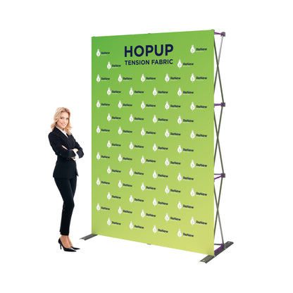 Trade show tension fabric display with branded backdrop and businesswoman showcasing exhibition booth