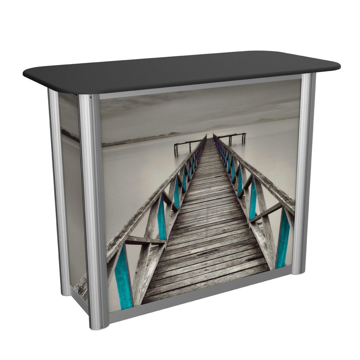Compact trade show counter with printed graphic panel depicting a wooden pier extending into calm water