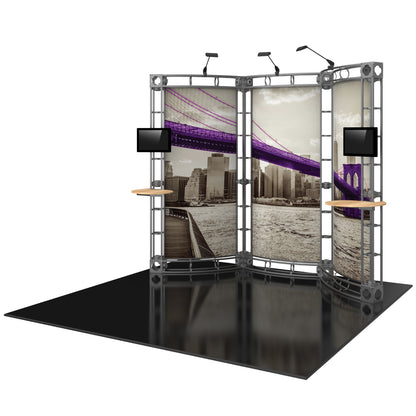 Curved truss display booth with printed cityscape panels, mounted monitors, and small shelves for trade shows