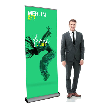 Retractable banner stand displaying dance studio advertisement with a man in business suit standing next to it for trade shows