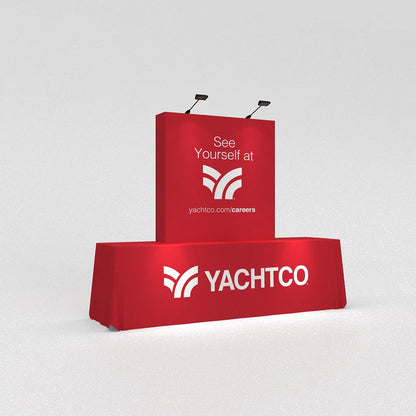 Trade show display with branded fabric table cover and backdrop booth featuring company logo and career message