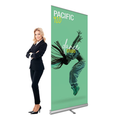 Retractable banner stand with dance studio promotion displayed next to businesswoman at trade show