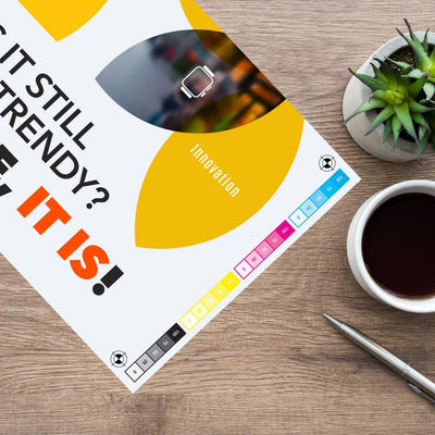 Printed proof sheet for trade show exhibits next to coffee, pen, and succulent on wooden table