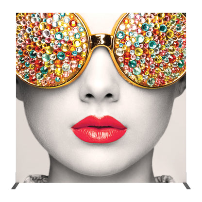 Large exhibition backdrop featuring close-up image of face with jeweled sunglasses and vibrant lips for trade shows