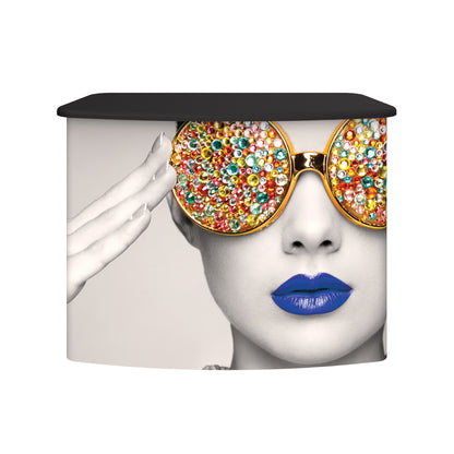 Curved fabric trade show counter with black top and vibrant printed graphic of woman wearing jeweled sunglasses and bold lipstick