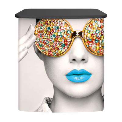 Trade show counter displaying large creative graphic of face with jewel-studded sunglasses and vibrant lips
