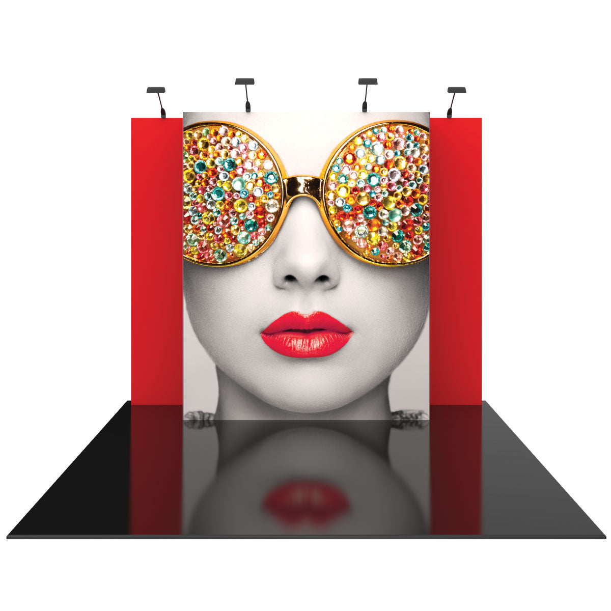 Trade show display featuring a large face graphic with bejeweled sunglasses and bright lips, set against a backdrop with side panels and overhead lights