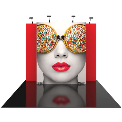 Trade show display featuring a large face graphic with bejeweled sunglasses and bright lips, set against a backdrop with side panels and overhead lights