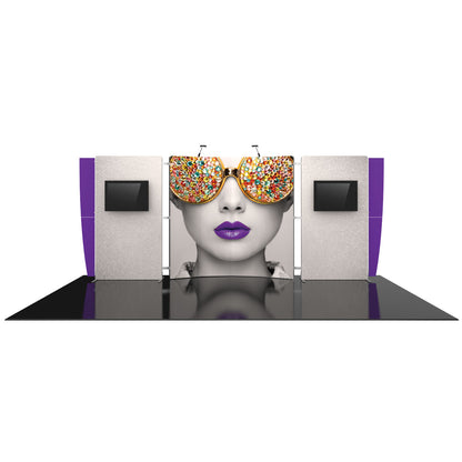 Trade show booth with large graphic panel featuring a woman's face with jeweled sunglasses and purple lips, flanked by display monitors and lighting