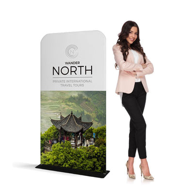 Trade show banner stand displaying travel tours promotion next to a professional woman