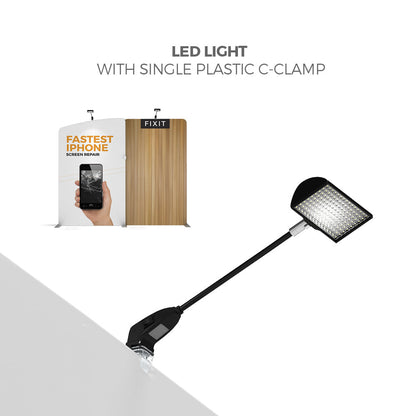 LED light with plastic C-clamp attached to trade show display panel for exhibition lighting