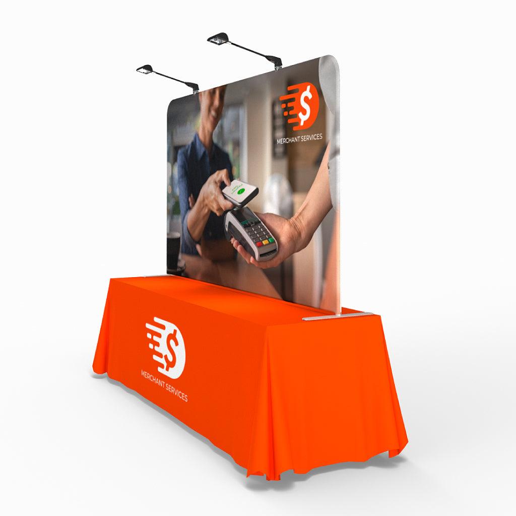 Trade show tabletop display with branded table cover and curved backdrop featuring merchant services payment image