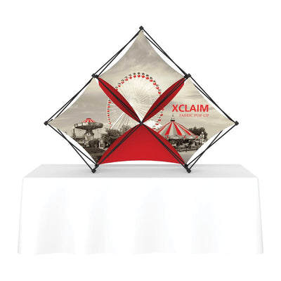 Xclaim fabric pop-up display with carnival print on table, ideal for trade shows and exhibitions